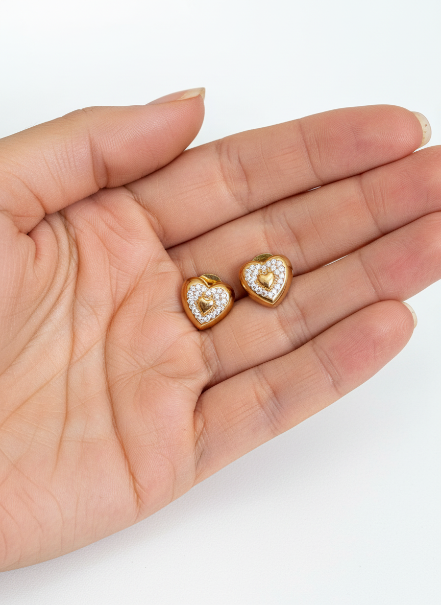 Brincos de coração dourados na palma da mão