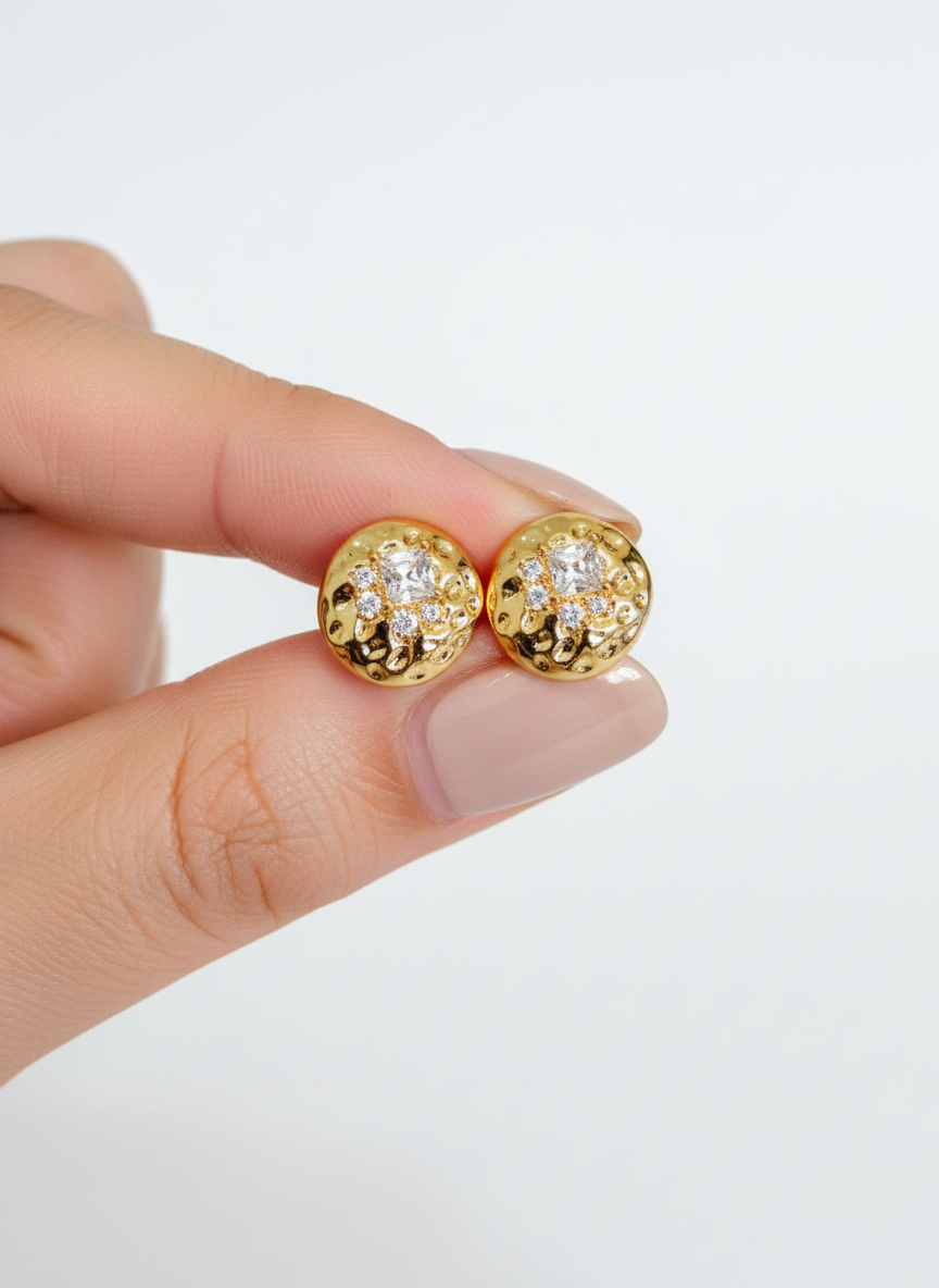 Mão segurando brincos de ouro